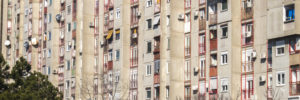 Young children play soccer on a concrete field in front of several concrete towers that belong to a mass housing project in Belgrade