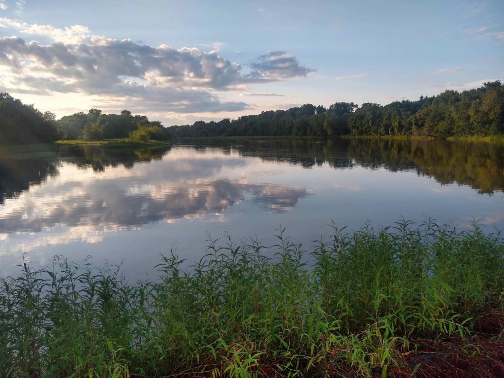 A photograph of Dresser Island, a lake with still waters reflecting clouds